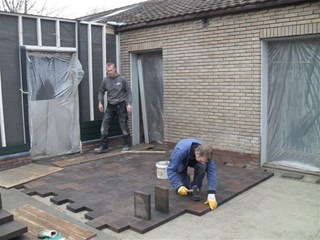 kees bestraat het pleintje voor de ingang en de slaapkamers